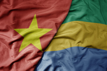 big waving realistic national colorful flag of vietnam and national flag of gabon .