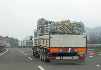 truck for transporting scaffolding irons from a construction site travels fast on the highway - obrazy, fototapety, plakaty