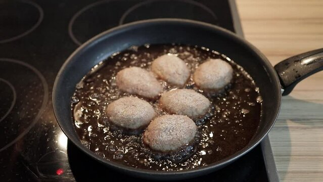 Raw meatballs with breadcrumbs on the pan with lots of oil