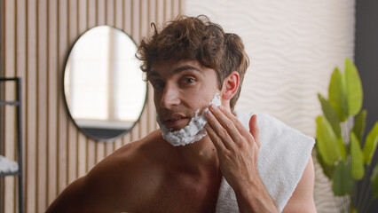 Close up Caucasian bearded male funny man guy looking at camera beauty routine morning hygiene...