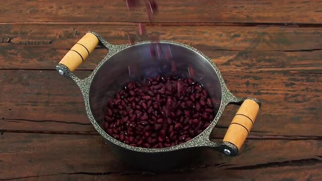 Grains of raw red beans falling into the pan
