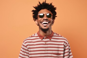 Obraz premium A suave man in sunglasses and a striped shirt stands against a wall, his jawline sharp and smile cool, exuding effortless style and confidence