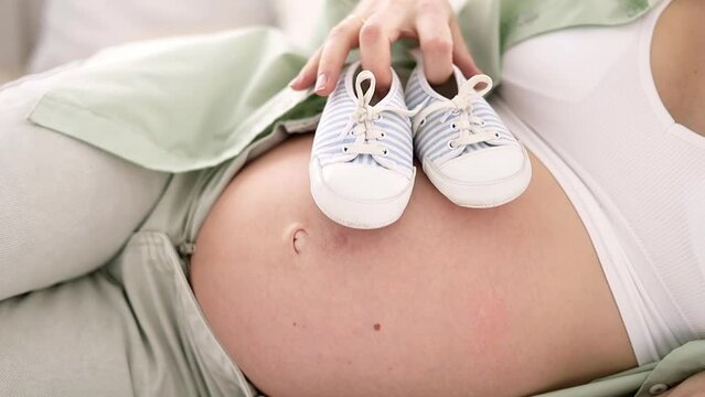 close-up belly of a pregnant woman with blue socks Pregnancy, motherhood, preparation and waiting concept