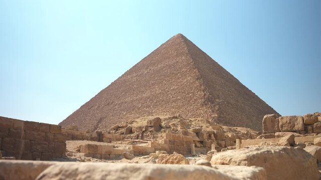Slow motion low angle slide shot of The Great Pyramid of Khufu or Cheops in Giza. Birds flying in the foreground. Cairo, Egypt. Ancient mystical Wonders of the World