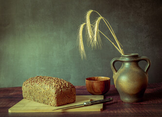 Rustic still life in antique style with bread and ears of wheat . - 651621925
