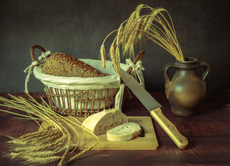 Rustic still life in antique style with bread and ears of wheat . - 651621977