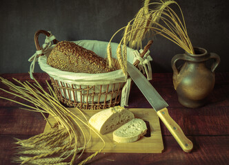 Rustic still life in antique style with bread and ears of wheat . - 651621985