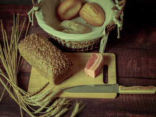 Rustic still life in antique style with bread, ears of wheat and ham and bacon. - 651622311