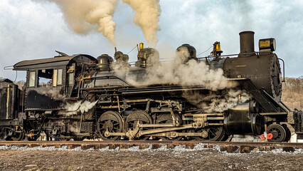 A View of a Restored Narrow Gauge Steam Locomotive Blowing Smoke and Steam on a Winters Day