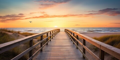 Serene sunset overlooking calm beach. Tranquil beginnings. Peaceful sunrise on ocean shore. Wooden path to paradise. Relaxing beachside boardwalk at dawn - obrazy, fototapety, plakaty