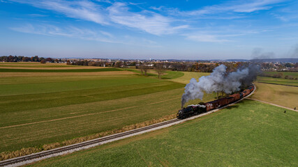 An Aerial View of a Steam Freight Train Approaching Around a Curve Blowing Smoke on a Sunny Autumn Day