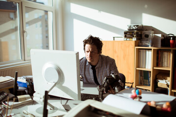 Young Caucasian male photographer going over his work on the computer in a media company office