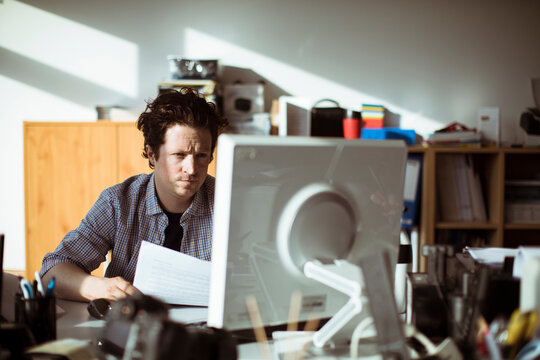 Young Caucasian man going over paperwork while working in a media company office