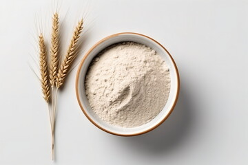 Wheat flour in wooden bowl and ears isolated on white