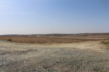 Fototapeta premium A dirt road with grass and hills in the background