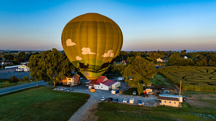 Obraz premium An Aerial View of a Golden Hot Air Balloon, Just Launched and Floating Across a Field on a Sunny Summer Morning
