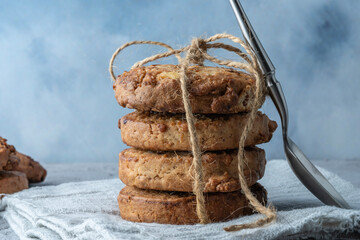 A stack of cookies tied with linen thread on a linen napkin with close-up and a teaspoon.