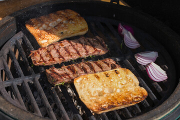 outdoor grilling venison meat from a chamois on the charcoal grill with bread and red onions at  sunny autumn day