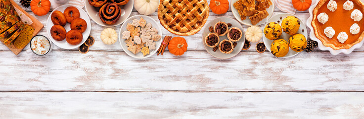 Autumn desserts top border. Table scene with a collection of traditional fall sweet treats. Above view over a white wood banner background. Copy space.
