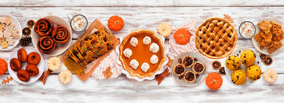 Autumn desserts table scene with a selection of traditional fall sweet treats. Overhead view over a white wood banner background.