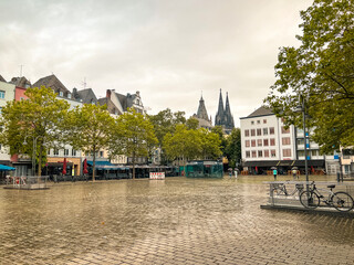 Heumarkt Square in Cologne, Germany on a rainy day. Views of colorful European architecture and cobblestone streets. Tourists with umbrellas gather in this over 2,000 year old city.
