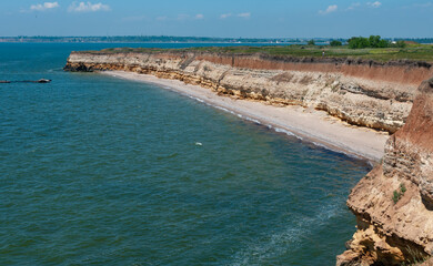 Steep clayey and shell rock shore overgrown with wild steppe vegetation on the island of Berezan,...