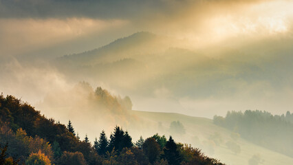Autumn misty mountainous landscape with morning sun rays shining through the clouds. The Orava region of Slovakia, Europe.