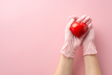 First person top-view perspective reveals female hands adorned in medical gloves, holding red heart...
