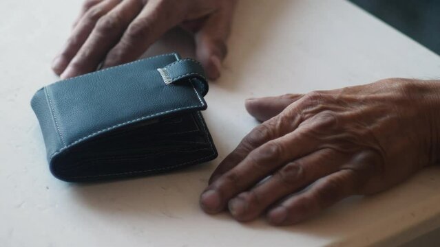 hands of a pensioner and a wallet on the table, concept of financial problems, bankruptcy of the elderly, pension savings, financial crisis, poverty in old age