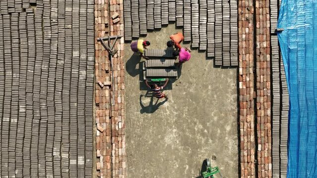 Workers in a brickfield or brick factory, making bricks from mud. The workers are surrounded by dust and heat, but they work hard to produce the bricks that are essential for building homes.