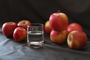still life, a glass of water and ripe apples, one apple hanging in the air
