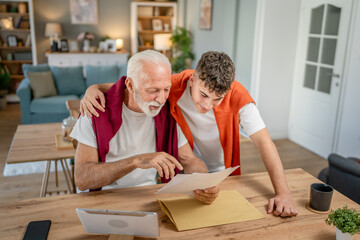 Senior man grandfather and caucasian man teenager boy grandson receive letter read good news...