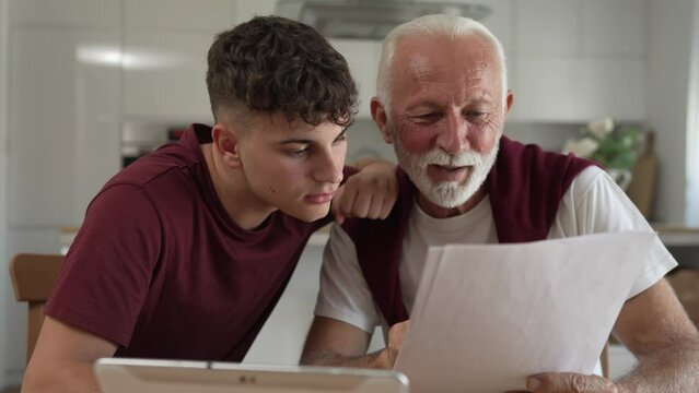 Senior man grandfather and caucasian man teenager boy grandson receive letter read good news student get scholarship or invitational letter from university share excitement real people slow motion