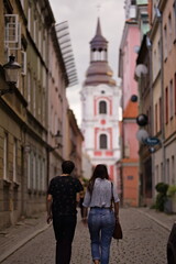 Sylwetki dwóch osób, turystów tyłem, idących w stronę Fary w Poznaniu