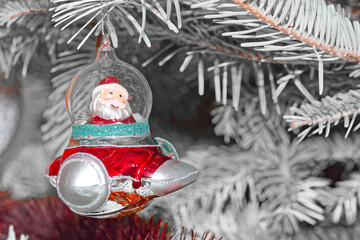 Santa Claus in a spaceship as Christmas tree decoration against white branches - 651713703