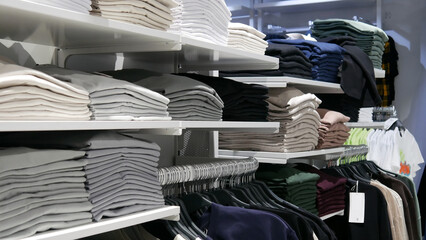 Many different clothes on the shelves and hangers in a clothing store