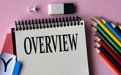 OVERVIEW - a word written in a notebook on a pink background and colored pencils