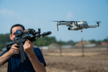 Man aiming to shoot a rifle at a flying drone outdoors. 