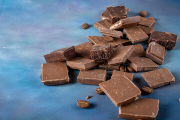 Cubes of milk and dark porous chocolate close-up on a blue background