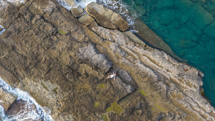 The girl sunbathing on the rocks in the sea.