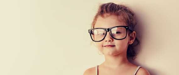 Funny smart kid girl in fashion glasses looking on empty copy space. Closeup - 651728996