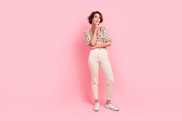 Full length photo of optimistic minded woman wear print top white pants look empty space hand on chin isolated on pink color background - obrazy, fototapety, plakaty