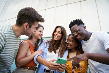 Diverse university students watching smartphones in college campus. Youth culture happy group of multiracial teens using mobile phone outdoors. Generation Z people having fun on city street - Powered by Adobe