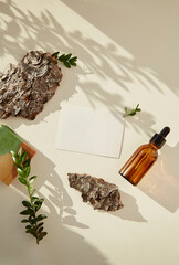 Stationery card mock up. Natural beauty products with sunny shadows. Dropper serum glass bottle of hyaluronic acid, natural soap among pebbles and tree bark