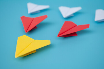 Side view of yellow paper airplane origami leading red and white paper airplanes. Leadership...