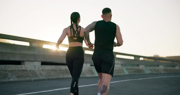 Couple, fitness and running in city for workout, outdoor exercise or training together in urban town. Rear view of active man and woman athlete or runners in sprint, cardio or sports marathon on road