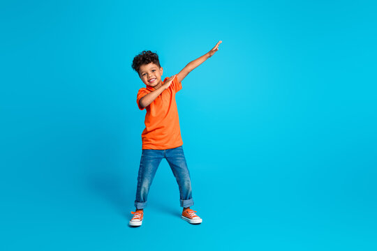 Full length body cadre of small boy kindergarten moves dab sign have fun dab demonstration dancing isolated on blue color background