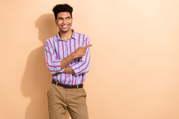 Photo of good mood man with afro hair dressed striped shirt look directing at discount empty space isolated on beige color background