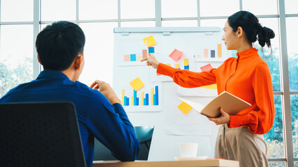 Young woman explains business data on white board in casual office room . The confident Asian businesswoman reports information progress of a business project to partner to determine strategy . Jivy
