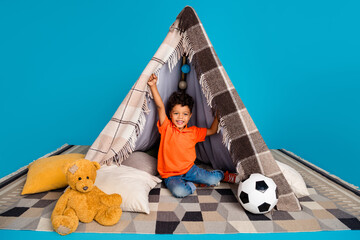 Photo of sweet preschool boy sleep awakening in diy tepee after afternoon sleep isolated blue color...